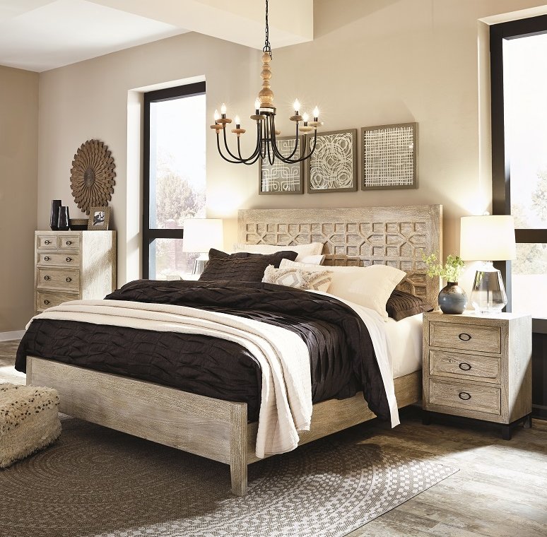 Large bedroom with cream colored wood with a chandelier hanging high above the bed and a nightstand with a lamp next to the bed.