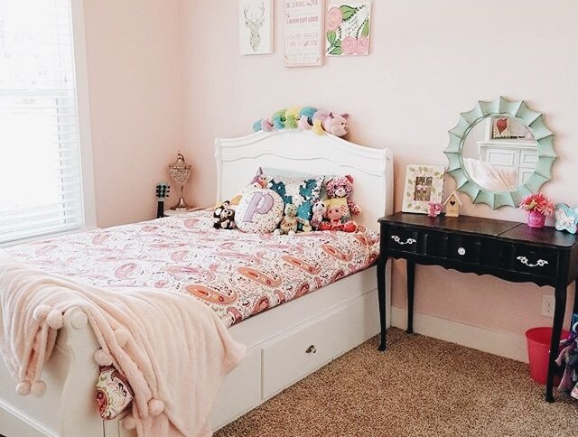Little girls room with wall decor above the bed.