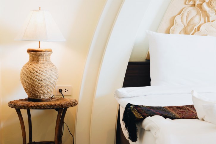 wicker lamp on table next to white bed