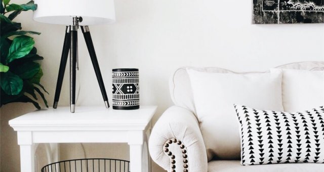 beige couch with white an black pillow next to white nightstand