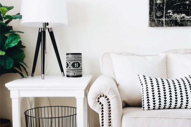 beige couch with white an black pillow next to white nightstand